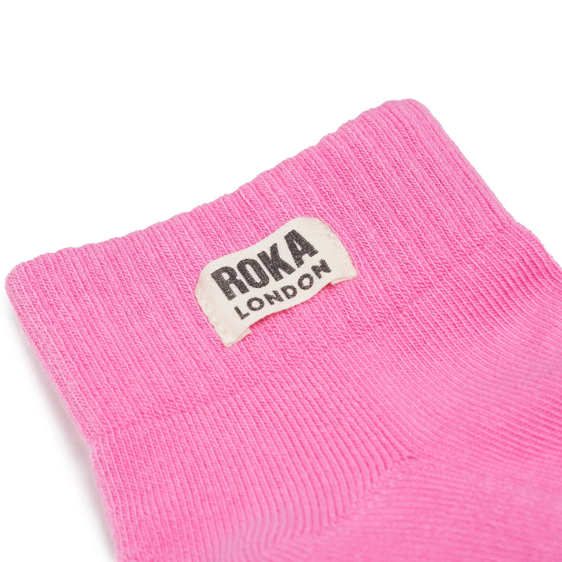 Pink sock with Roka London label on a white background