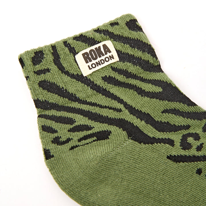 Green sock with black pattern and Roka London label on a white background