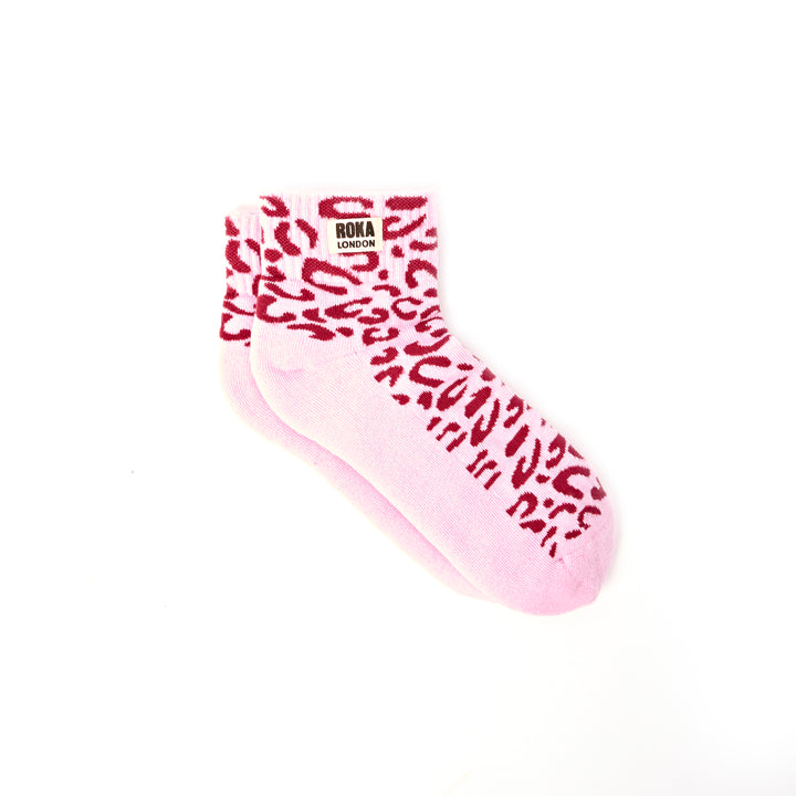 Pink sock with red leopard print pattern on a white background