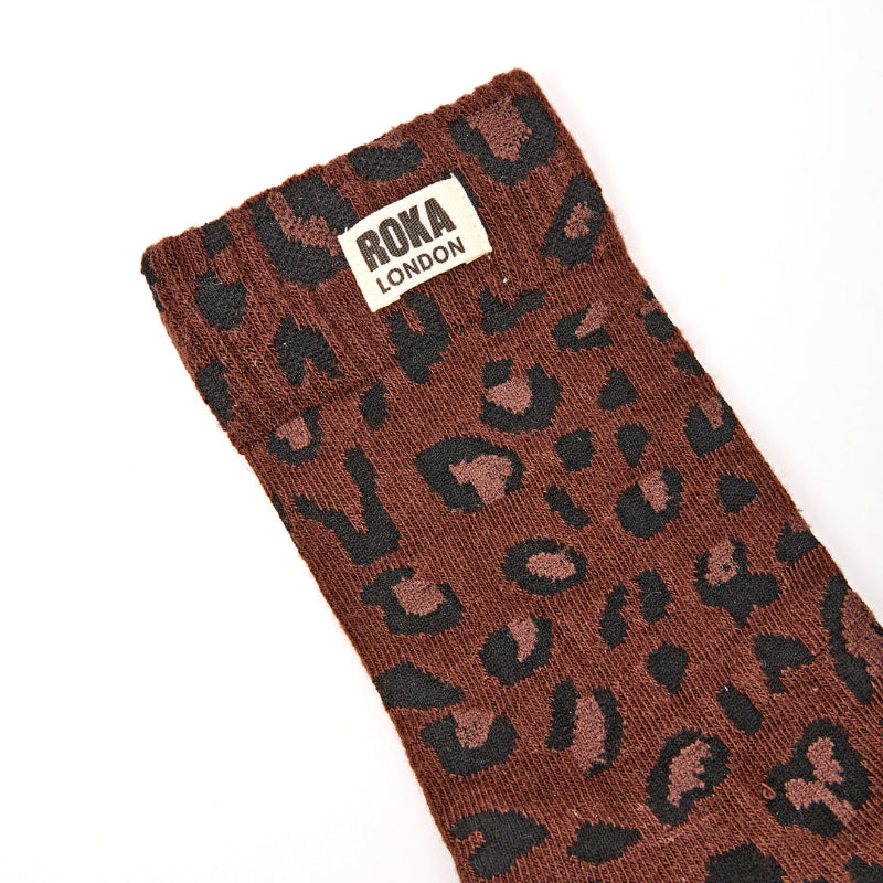Brown sock with black leopard print pattern and Roka London label on a white background