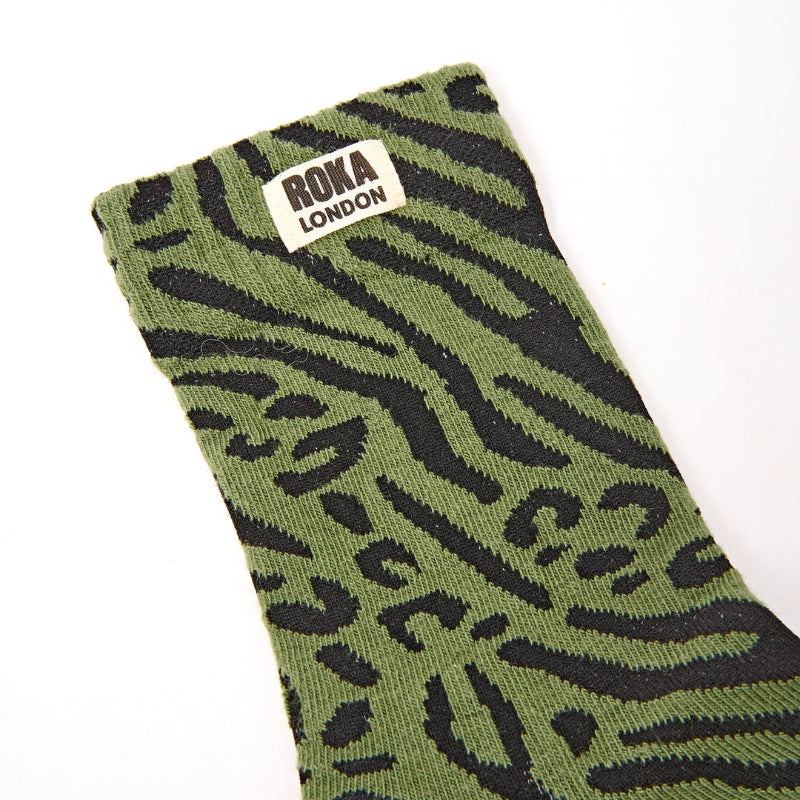 Green sock with black pattern and Roka London label on a white background