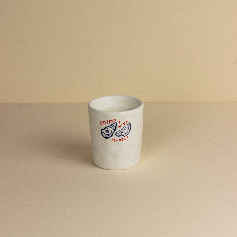 White ceramic candle with text and graphics on a beige background
