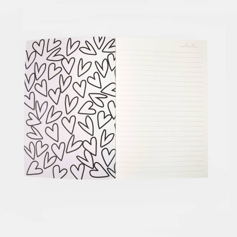 A lined notepad with a left cover panel covered in a black heart pattern on a white background, shown on a light gray studio background.