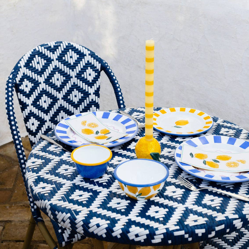table setting with blue and white patterned chair, colorful plates, and bowls on a matching tablecloth.