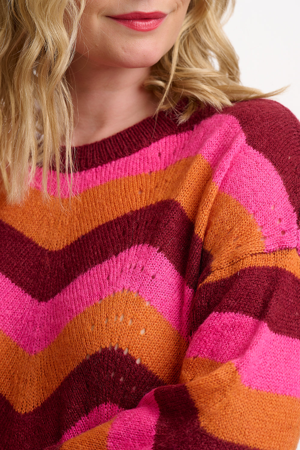 Close-up of a colorful striped sweater with pink, orange, and purple hues.