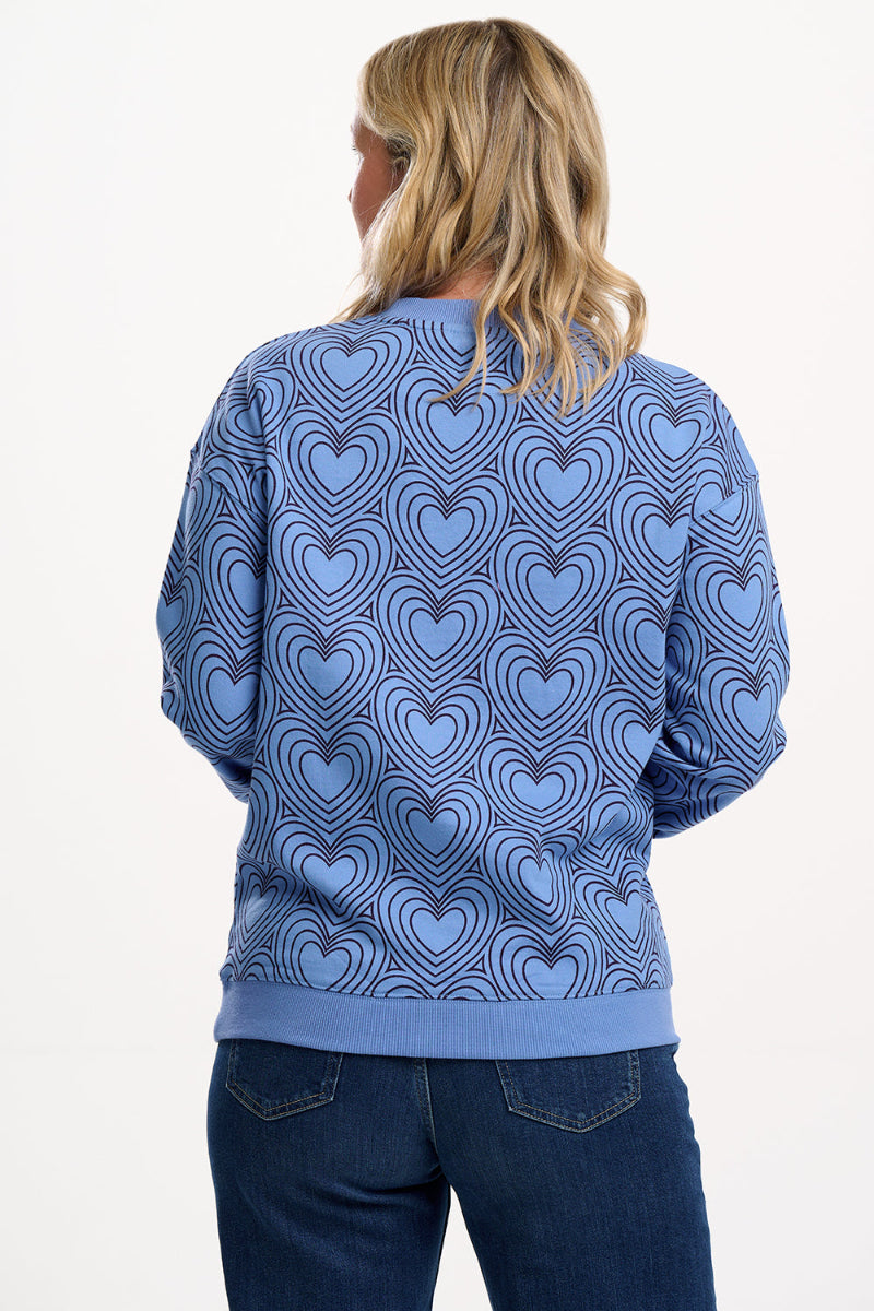 Person wearing a blue sweater with heart pattern on a white background