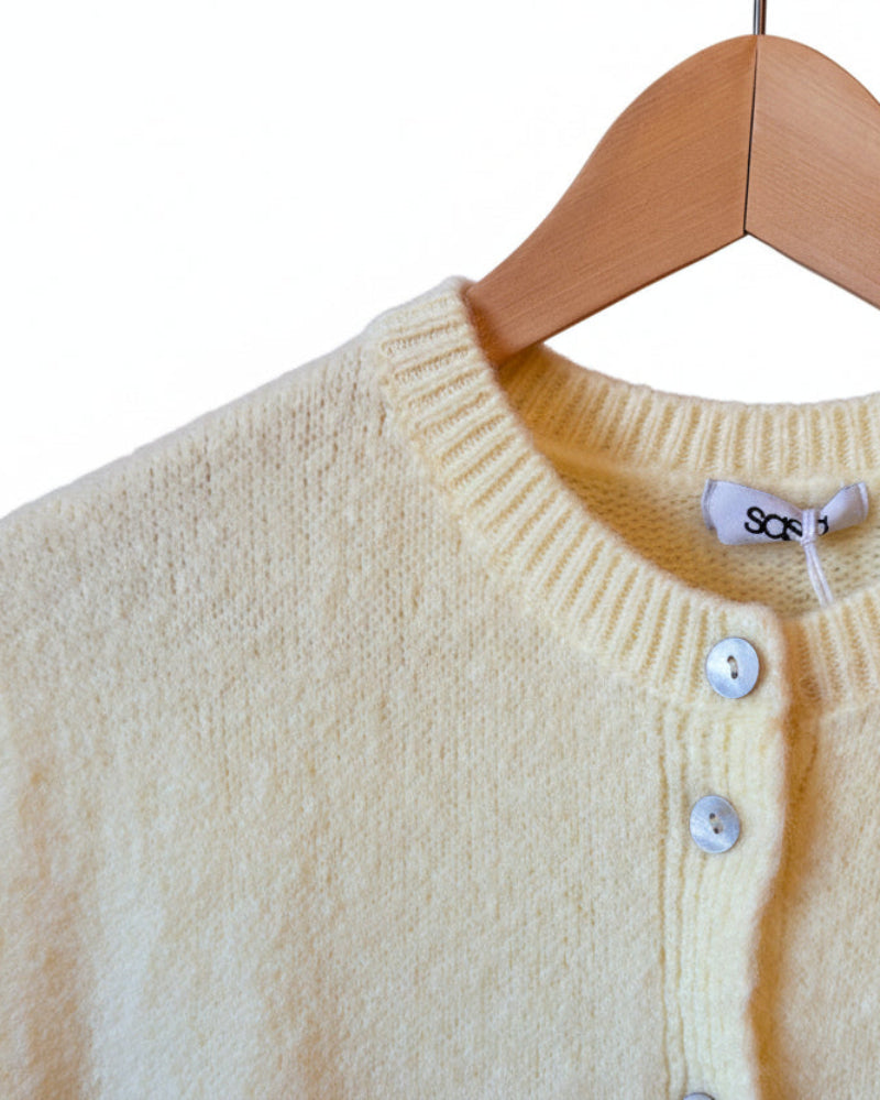 lemon yellow sweater with buttons on a wooden surface