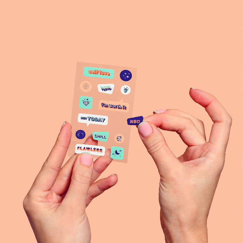 Hands holding a transparent sheet with various colorful stickers on a peach background