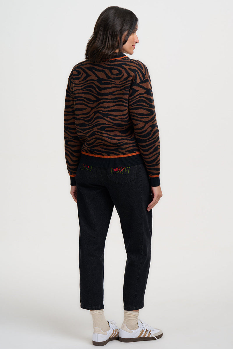Person wearing a zebra print sweater and black pants on a white background