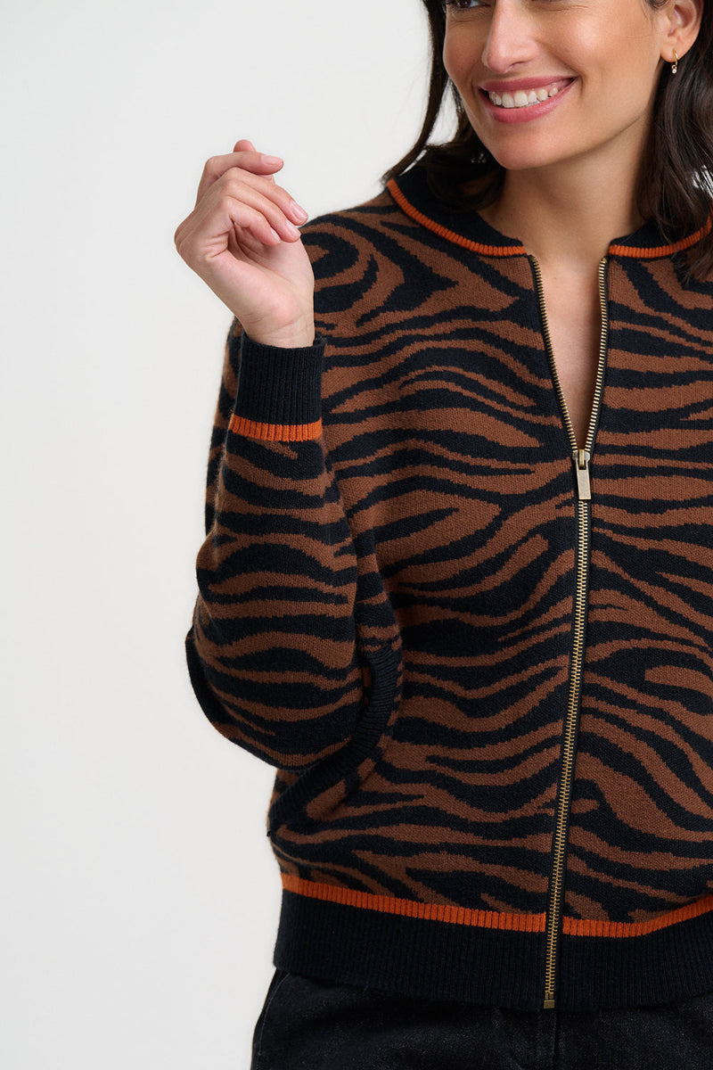 Woman wearing a brown and black zebra pattern jacket with orange accents on a white background