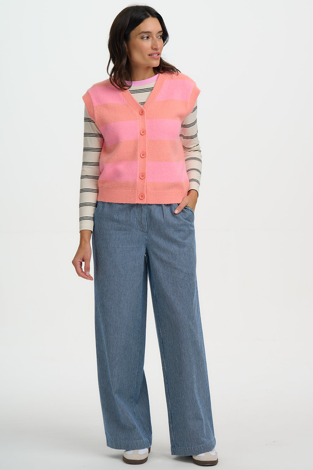 Person wearing a Sugarhill Amber Knit Vestover a striped shirt with blue jeans on a white background