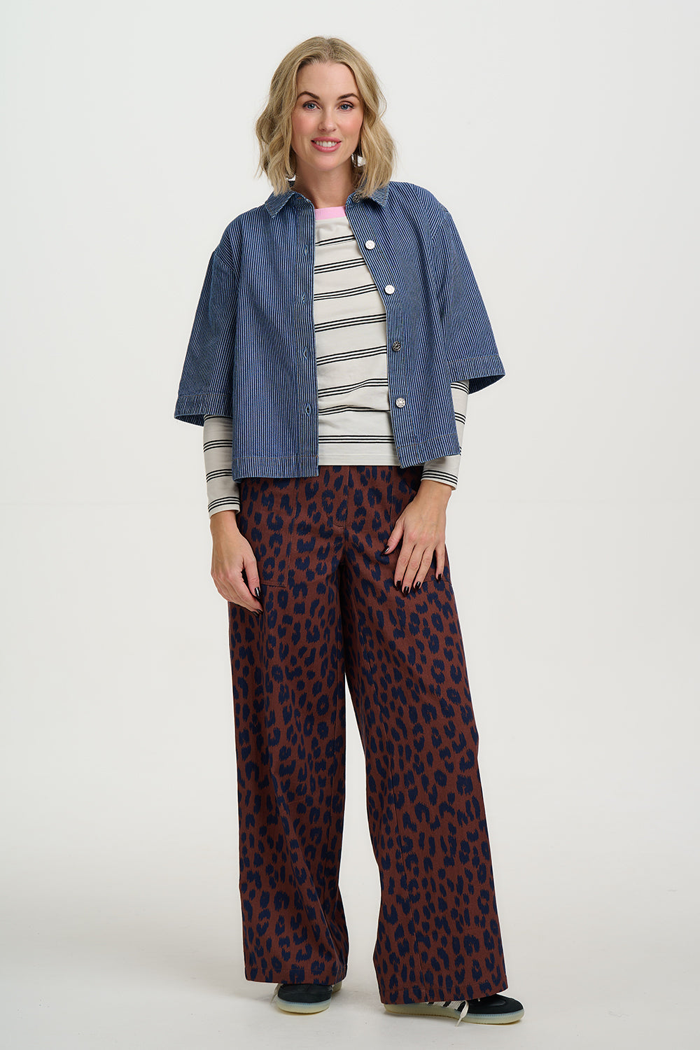 Woman wearing a Sugarhill Amity Jacket-Blue Stripe Denim striped shirt, and patterned pants on a white background