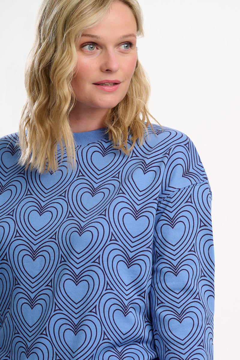 Woman wearing a blue sweater with heart pattern on a white background