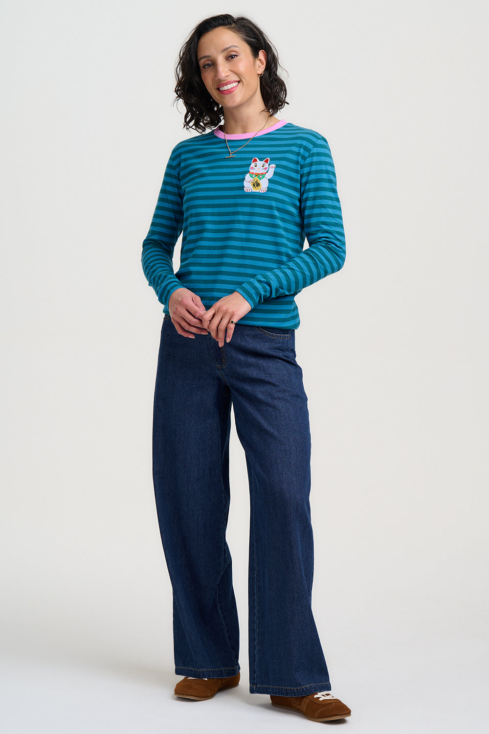 Woman wearing a Sugarhill Brighton Brunswick Lucky Cat Jersey Top and dark blue pants on a white background