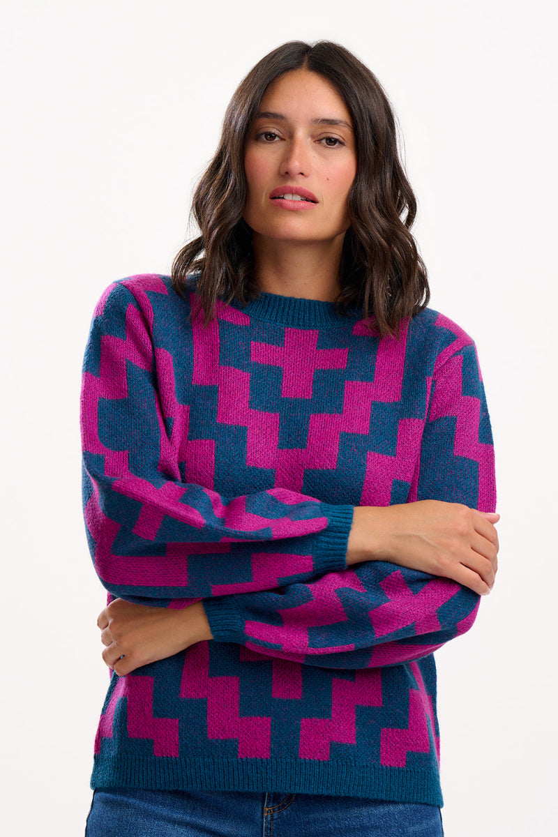 Woman wearing a Sugarhill Essie Jumper Teal/Pink Diamondon a white background