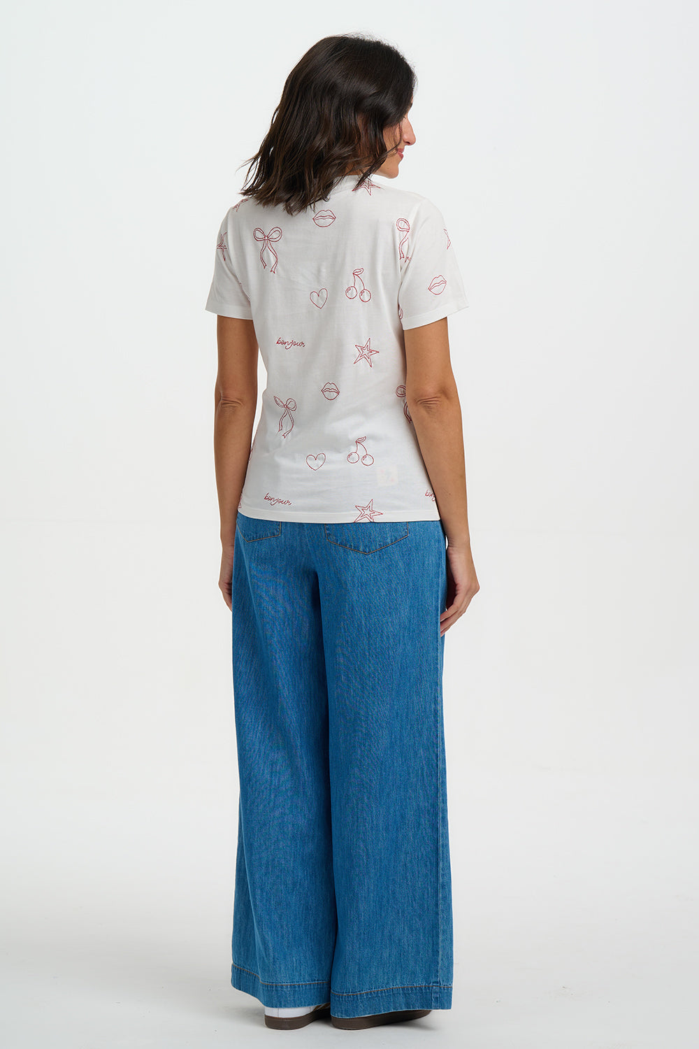 Person wearing a white t-shirt with red graphics and blue jeans on a white background
