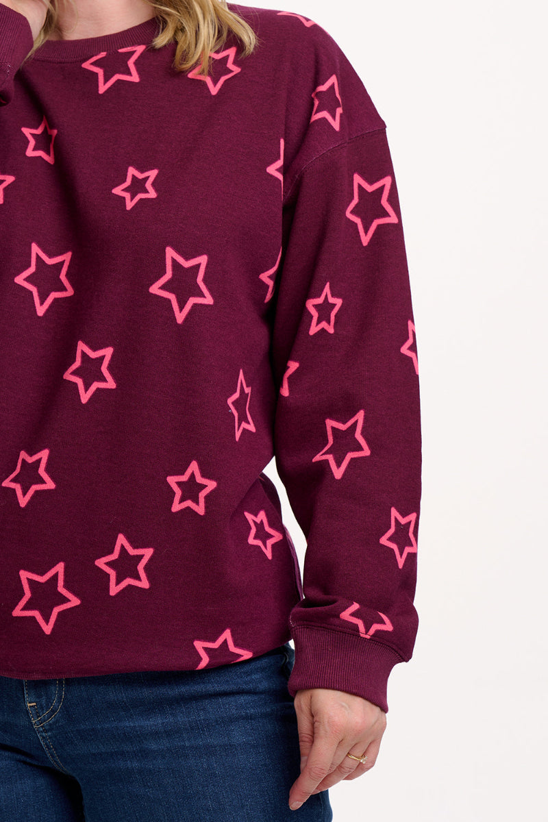 Maroon sweater with pink star patterns worn by a person