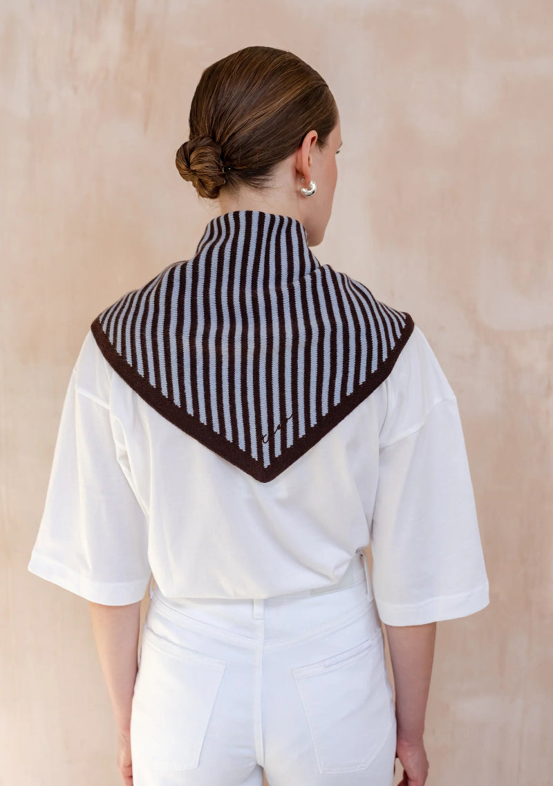 Person wearing a TBCO BLUE AND BROWN striped scarf on a beige background