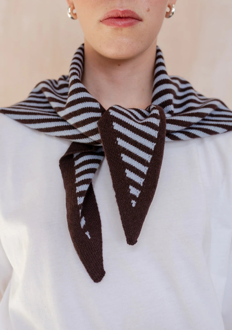 Person wearing a brown and white striped scarf on a plain background