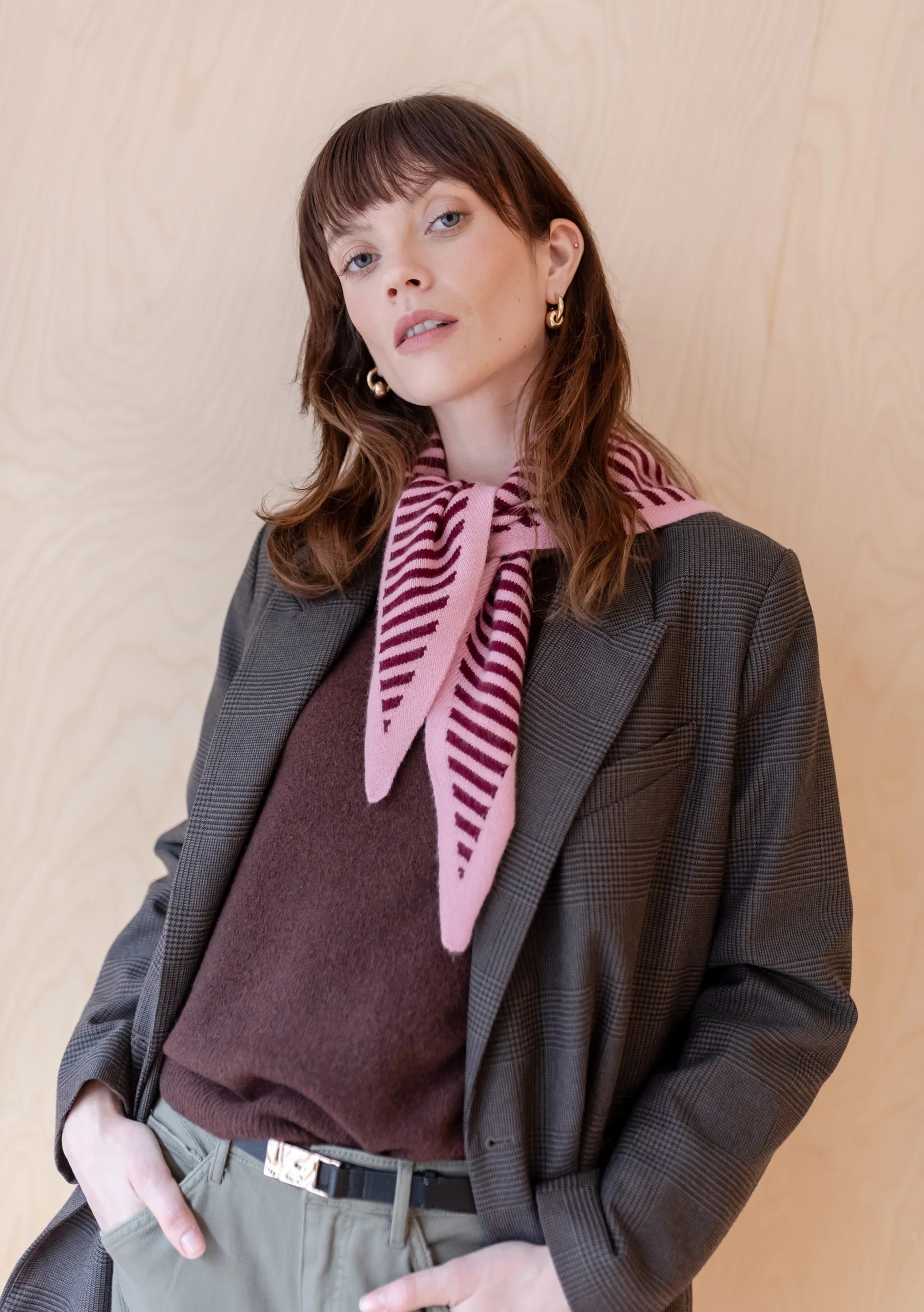 Woman wearing a TBCO pink striped scarf with a neutral background