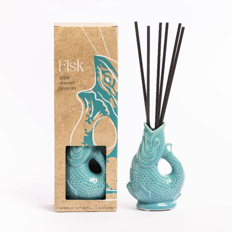 Teal ceramic diffuser with reeds and packaging on a white background