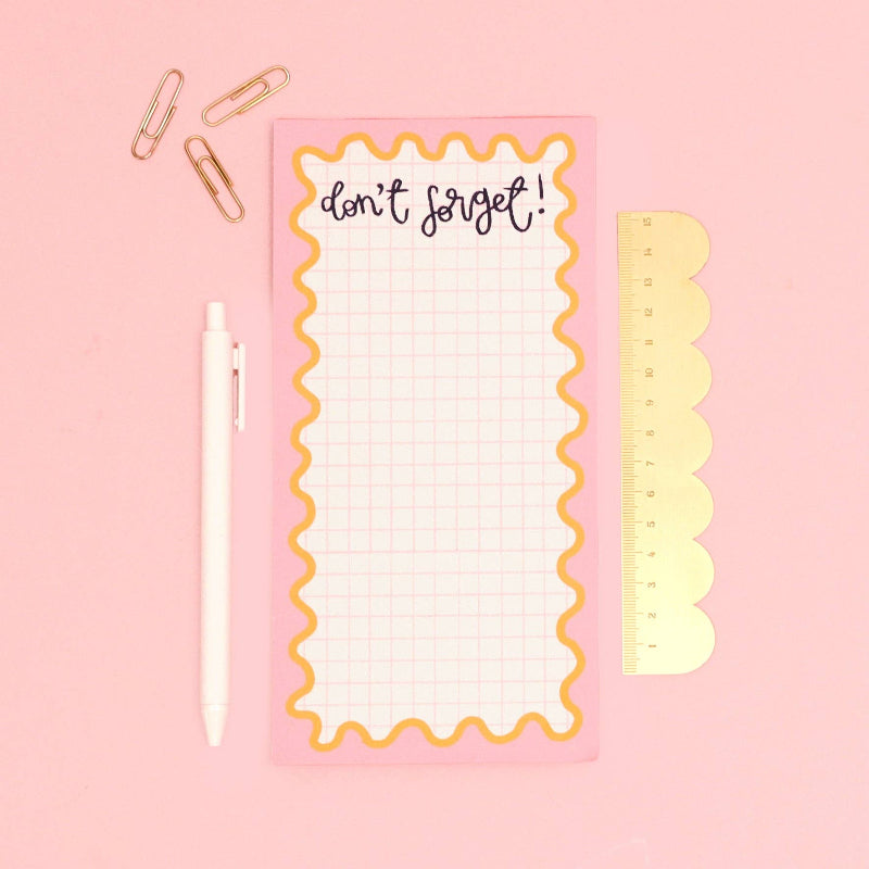 Notepad with grid, ruler, and 'don't forget!' text on a pink background