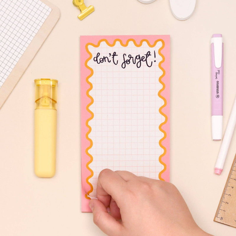 Notepad with 'don't forget!' text on a desk with stationery items