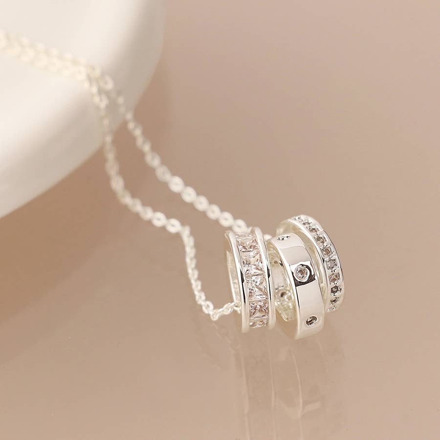 Silver necklace with circular pendants on a soft beige background