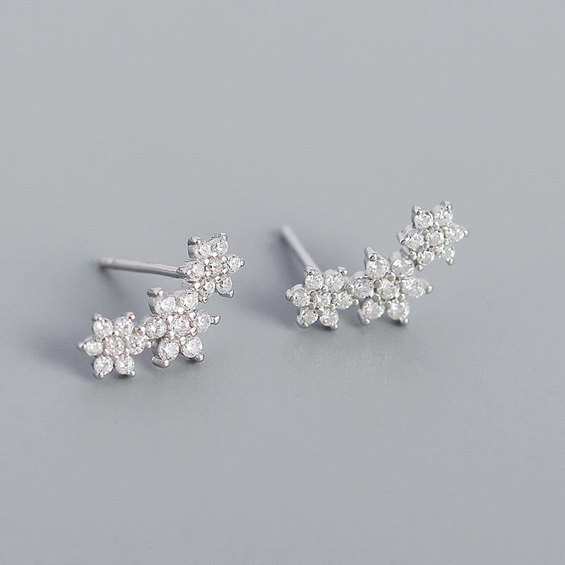 Pair of silver floral earrings on a gray background