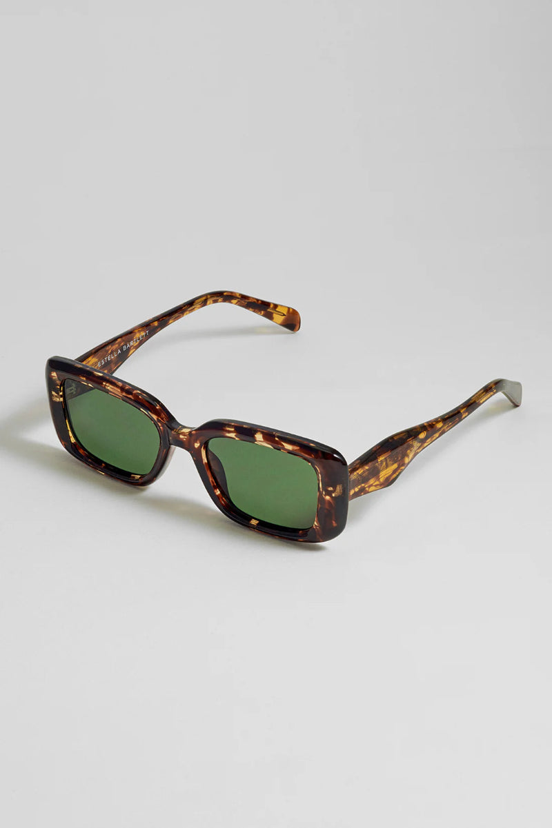 Sunglasses with tortoiseshell frame and green lenses on a light gray background