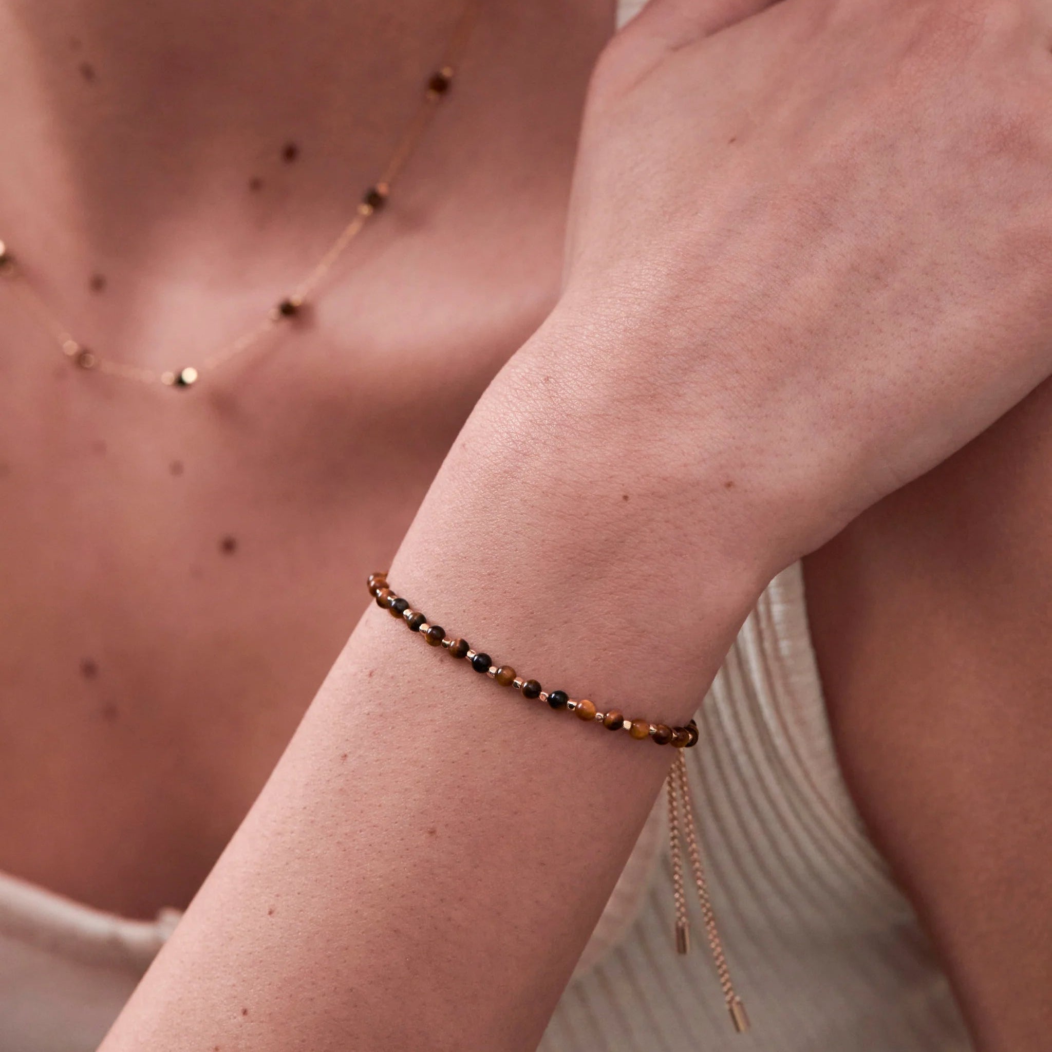 Close-up of a person wearing a beaded bracelet on their wrist with a neutral background