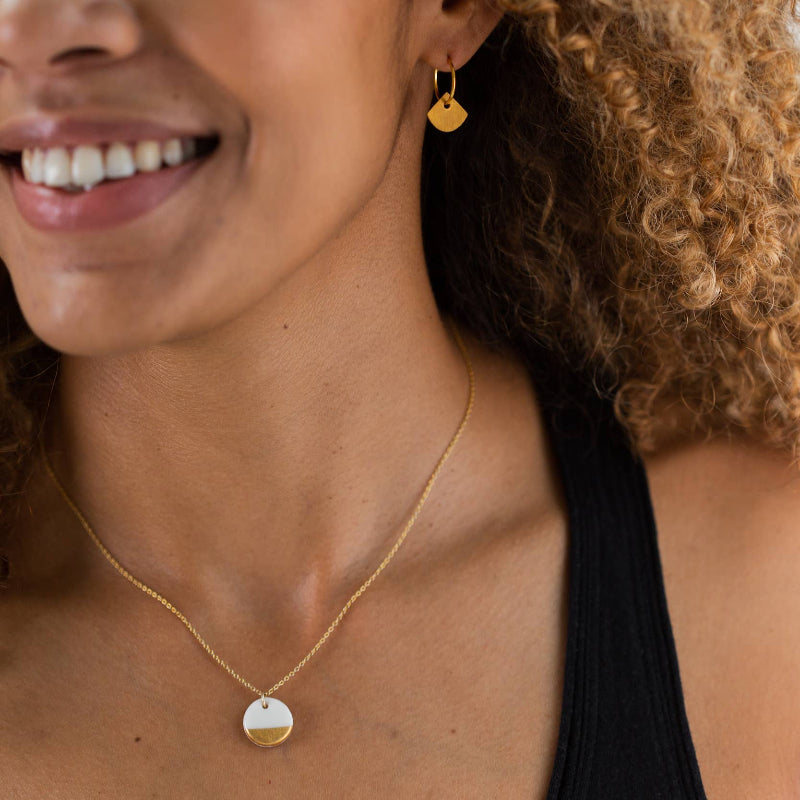 Woman wearing gold earrings and necklace with a blurred background