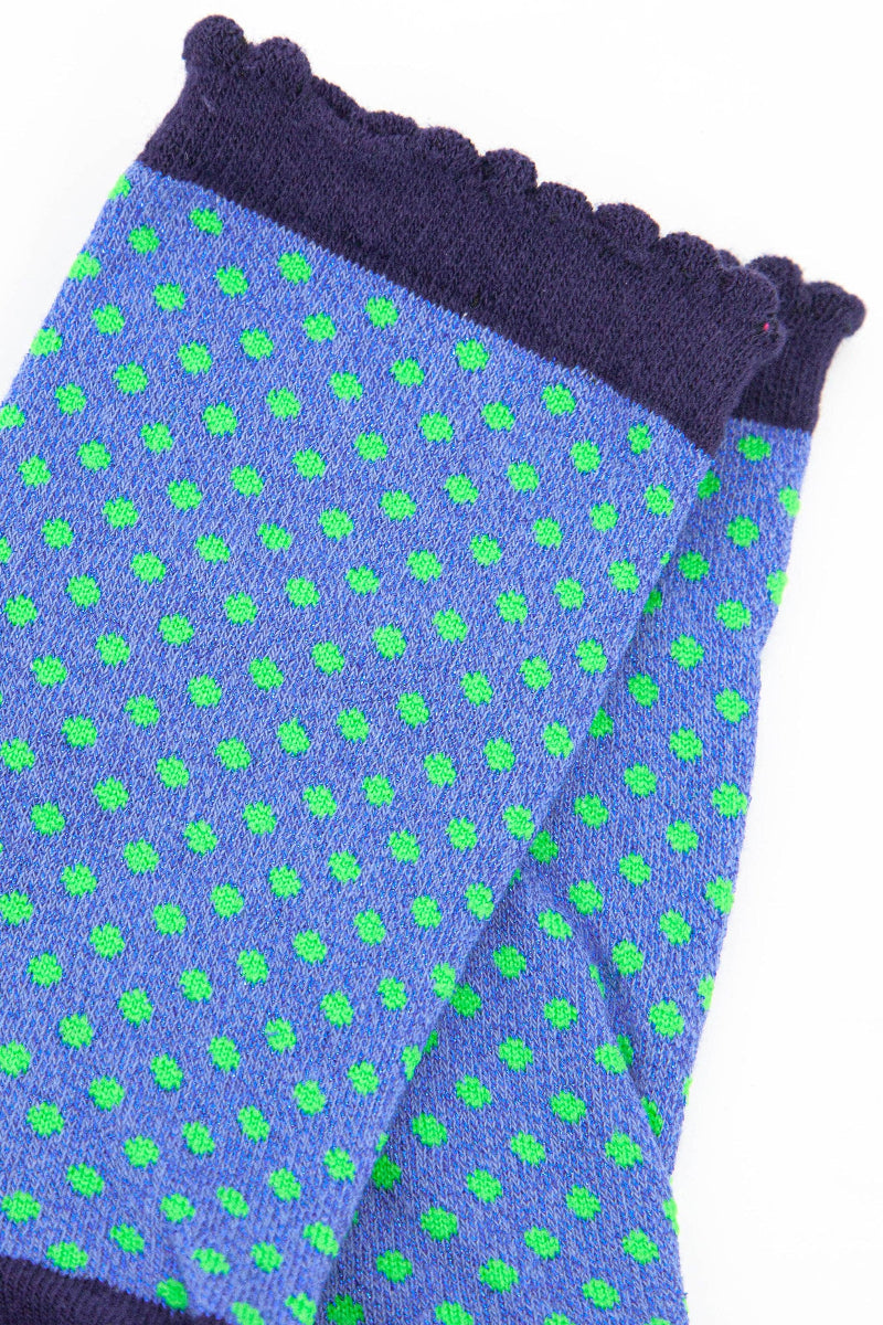 Pair of blue socks with green polka dots on a white background
