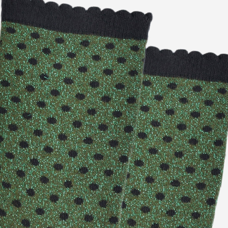 Green socks with black polka dots and black ribbed cuffs on a white background
