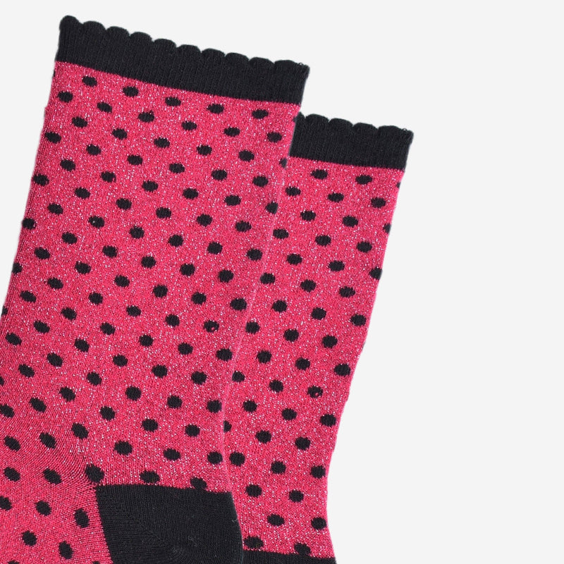 Pink socks with black polka dots and black cuffs on a light gray background