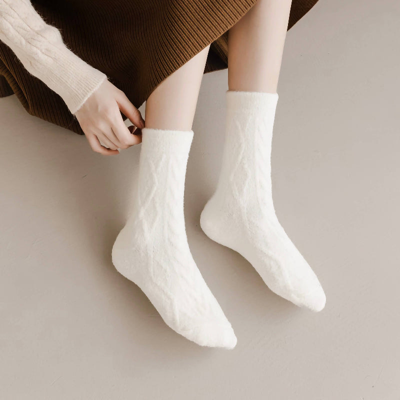 White cable knit socks worn by a person on a neutral background