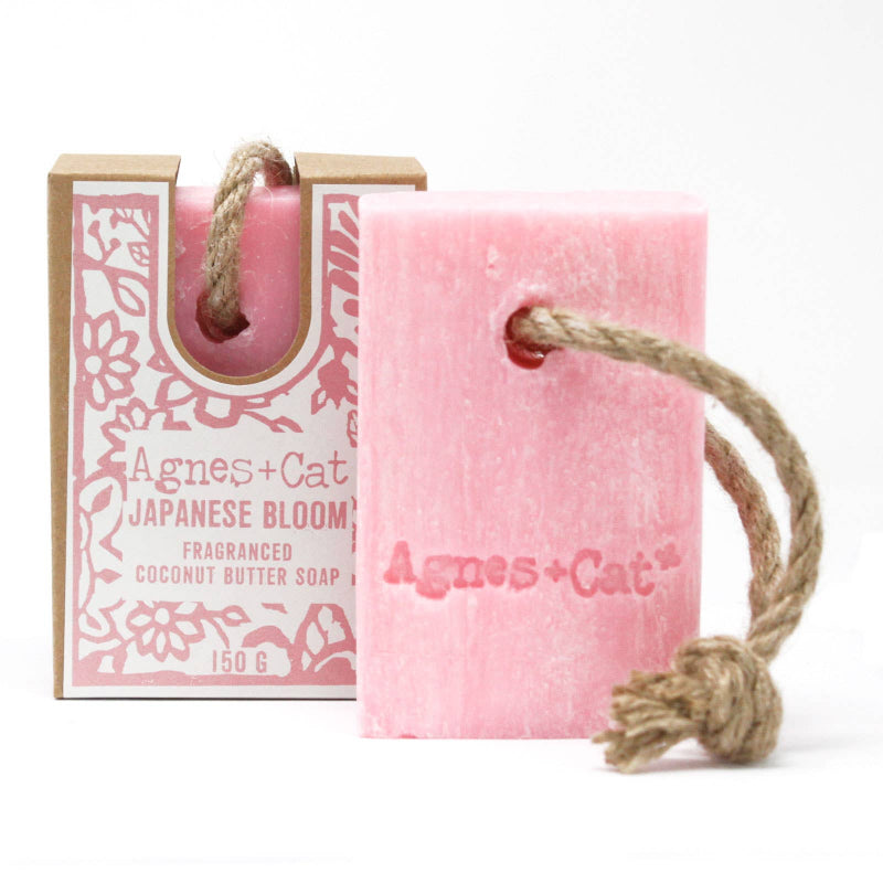 Pink soap bar with rope and packaging labeled 'Agnes + Cat' on a white background