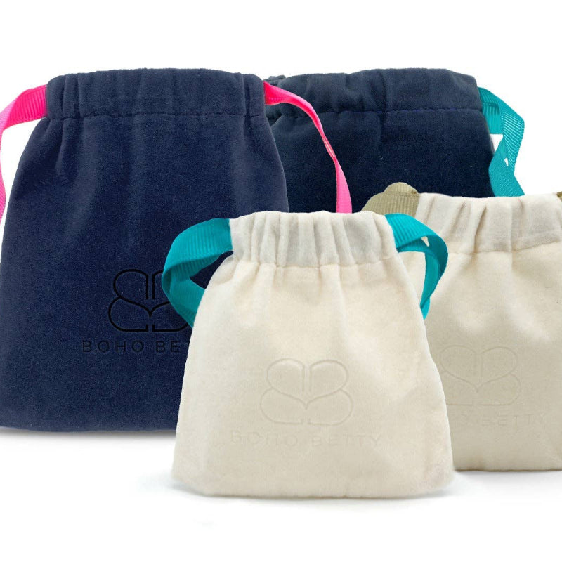 Three drawstring bags in navy, white, and beige with colorful strings on a white background.