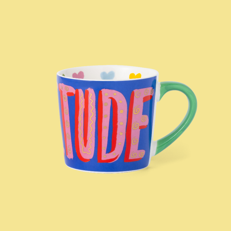 Mug with colorful letters spelling 'ATTITUDE' on a yellow background