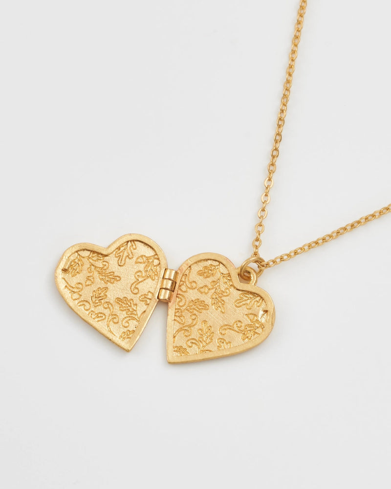 fable England Gold heart-shaped necklace with intricate designs on a light grey background