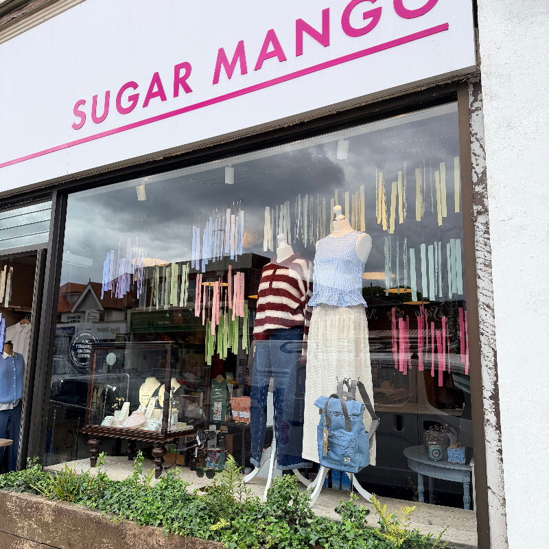 Storefront of Sugar Mango with mannequins and clothing displayed in the window.