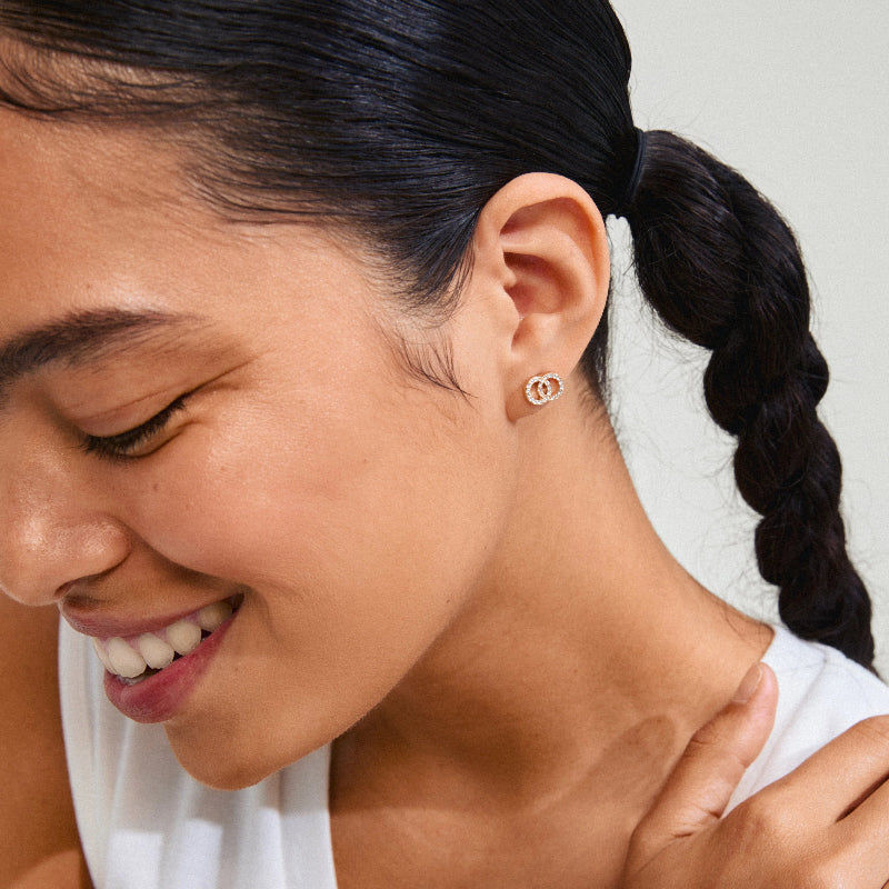 Woman with braided hair wearing Pilgrim Jolina Earrings Gold-plated, close-up of face and ear.
