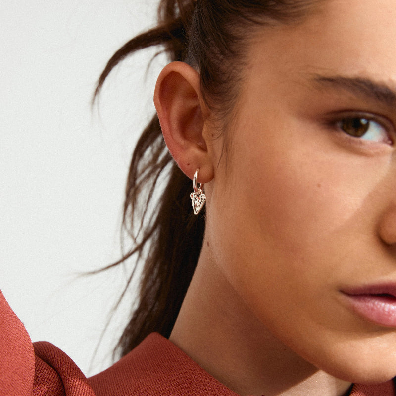 Close-up of a woman wearing a gold earring with a white background