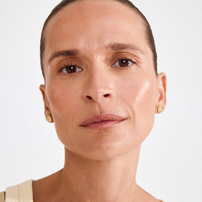 Close-up of a woman's face wearing Pilgrim Haze Earrings Gold Plated a light background