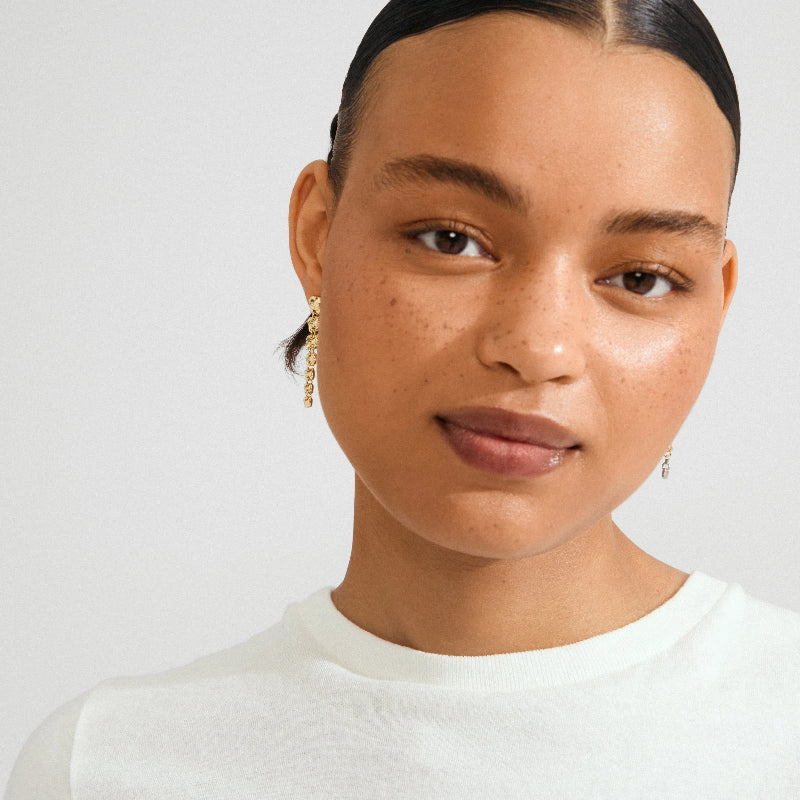 Woman wearing gold earrings against a plain background