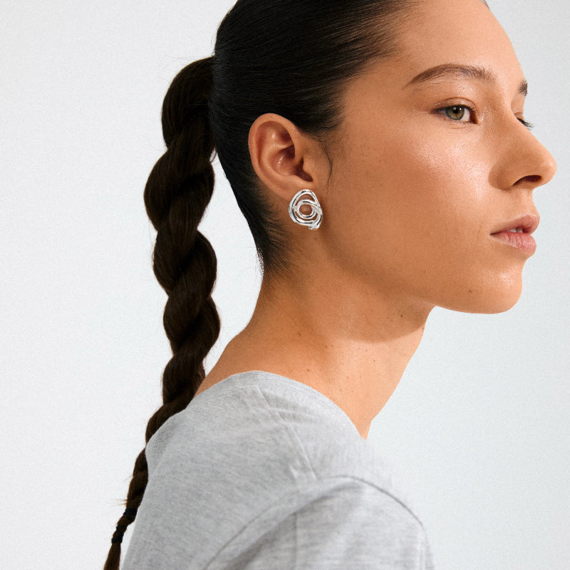 Woman wearing Pilgrim Unfold Earrings Silver-platedwith a plain background