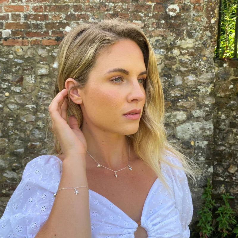 Woman wearing star-shaped jewelry against a stone wall background