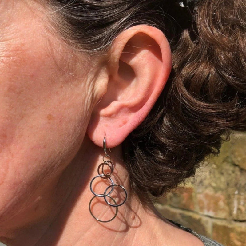 Close-up of an ear wearing a unique earring with circular designs.