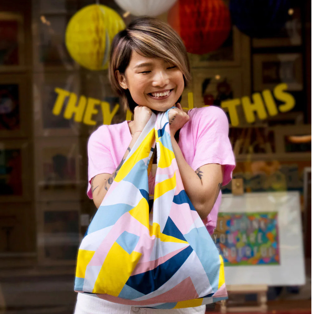 Person holding a colorful striped bag with a festive background