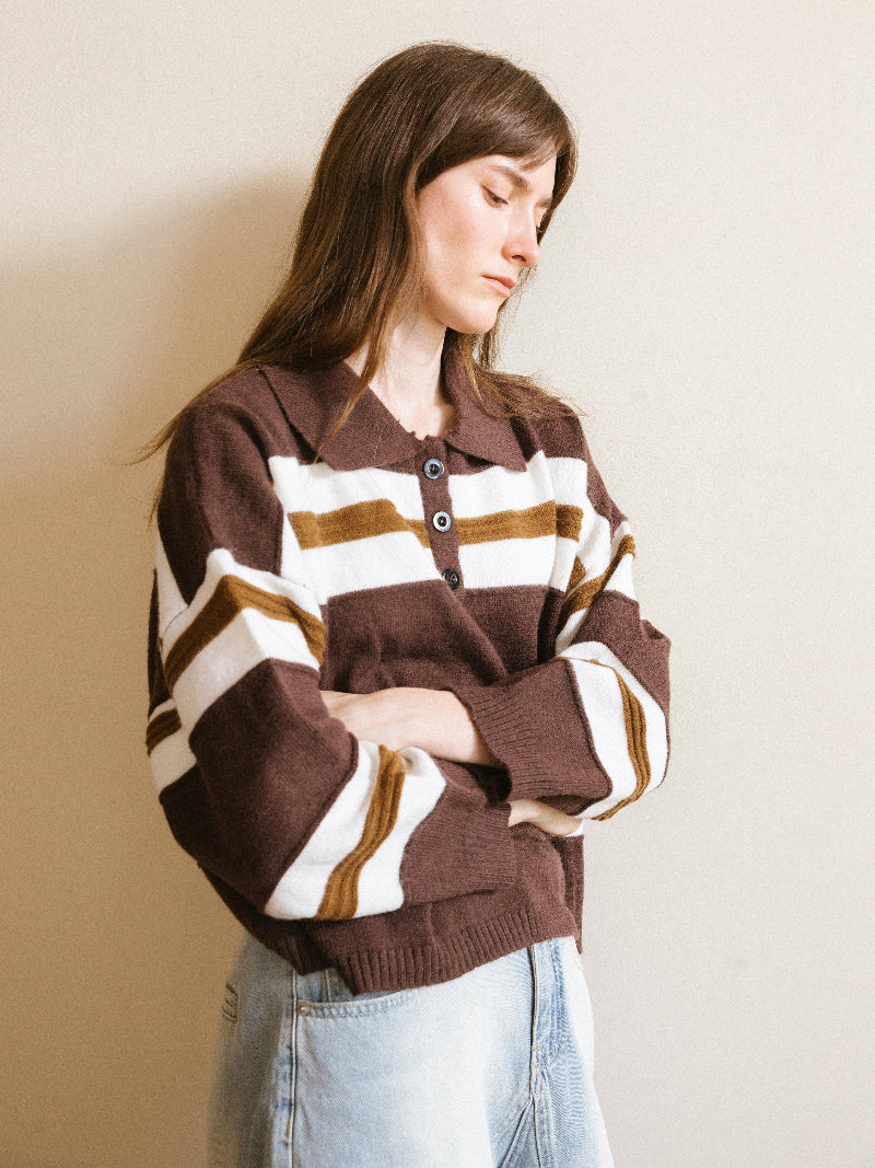 Model wearing a brown and white striped sweater against a beige wall